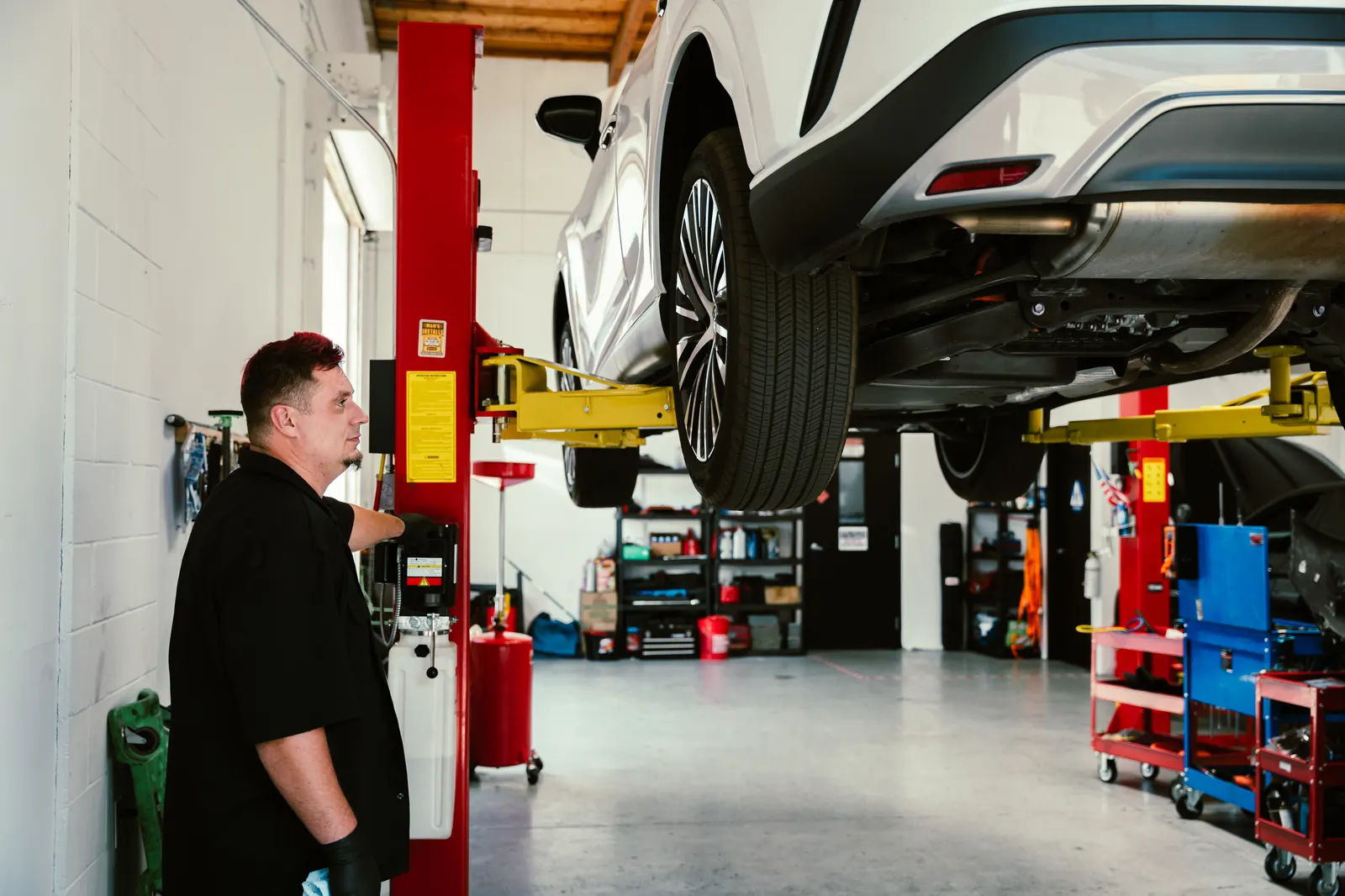 Mechanic preparing a vehicle for repair on a lift at Cali Car Care in Escondido, CA